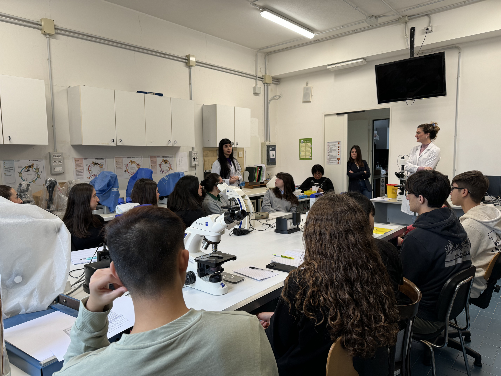 Studentesse e studenti partecipano a una spiegazione nel laboratorio di parassitologia, con diversi microscopi sui banchi
