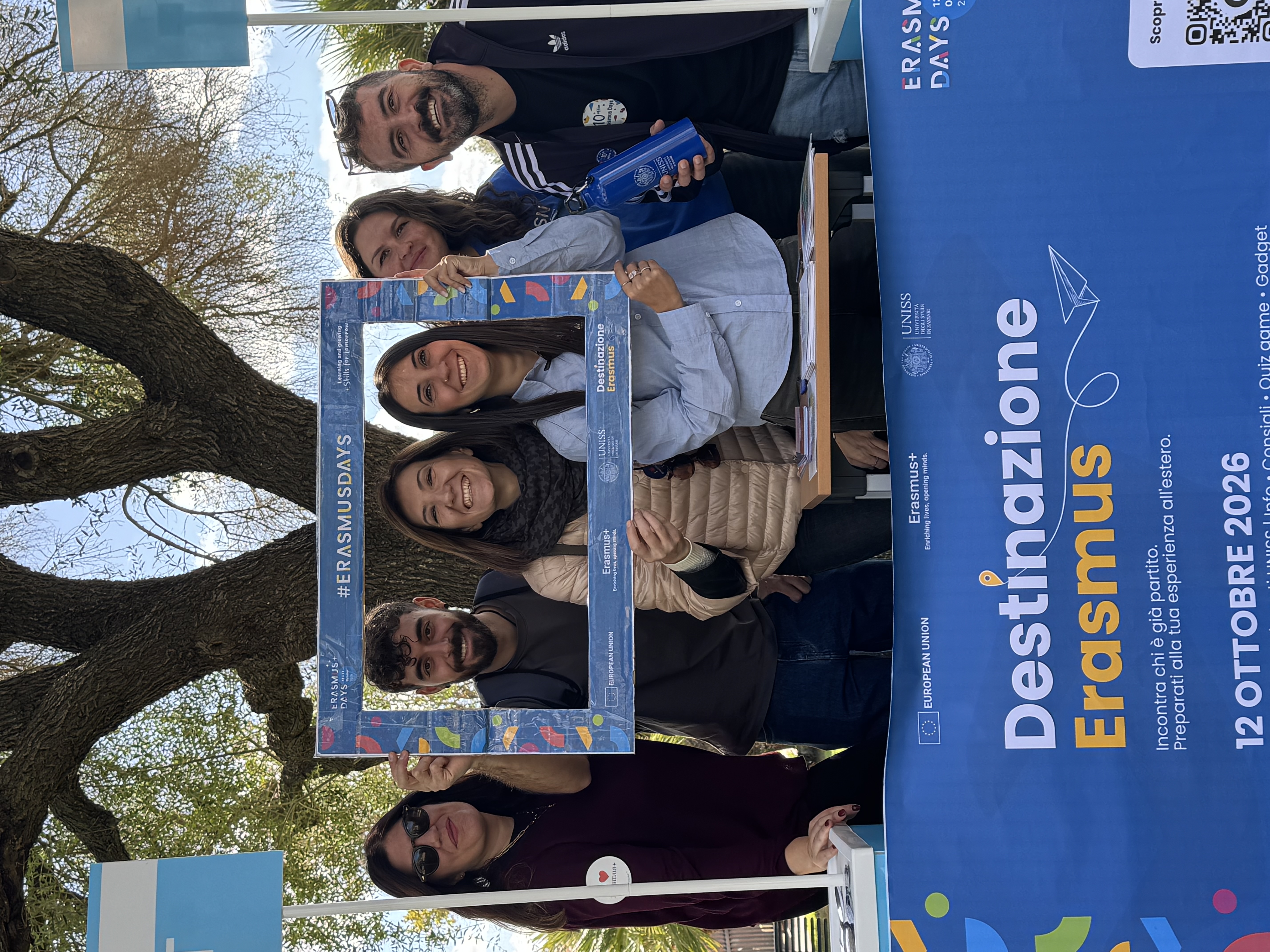Sei partecipanti posano sorridenti con una cornice fotografica degli Erasmus Days, dietro il banner di Destinazione Erasmus.